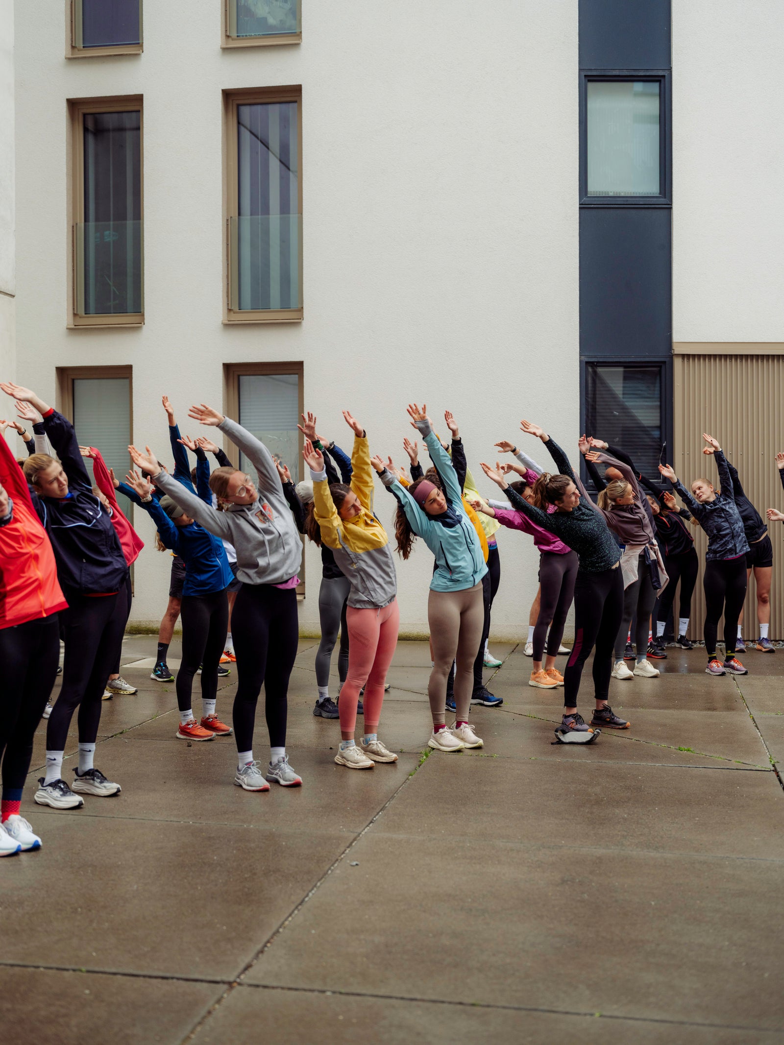 Group of people from a runclub stretching outdoors in front of a building