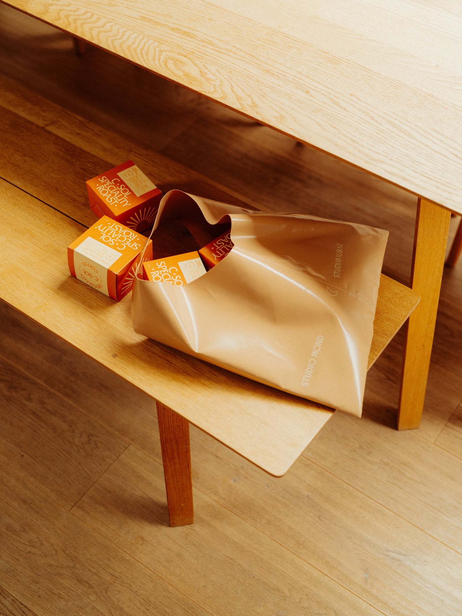 Wooden bench with a beige bag and orange coffee boxes on top