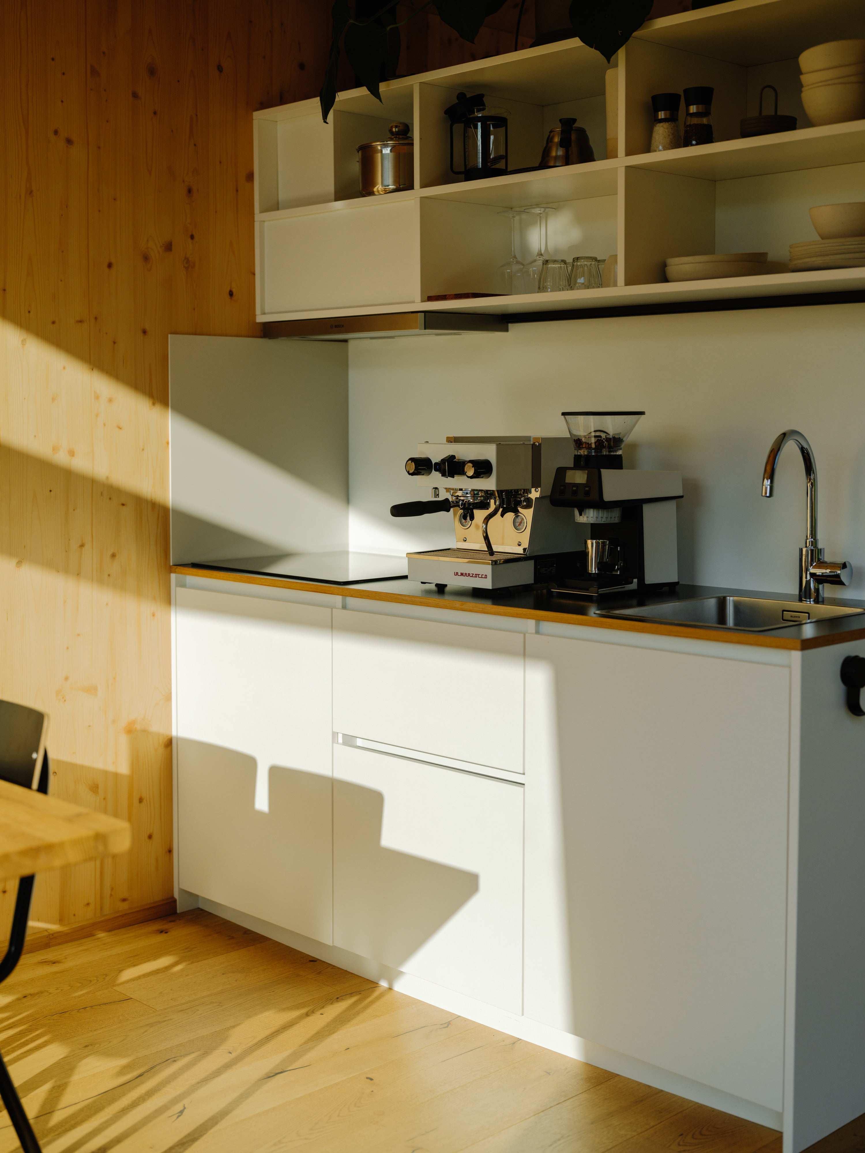 Modern kitchen with white cabinets, wooden countertop, and La Marzocco Micra coffee machine and La Marzocco Pico Grinder in a cabin