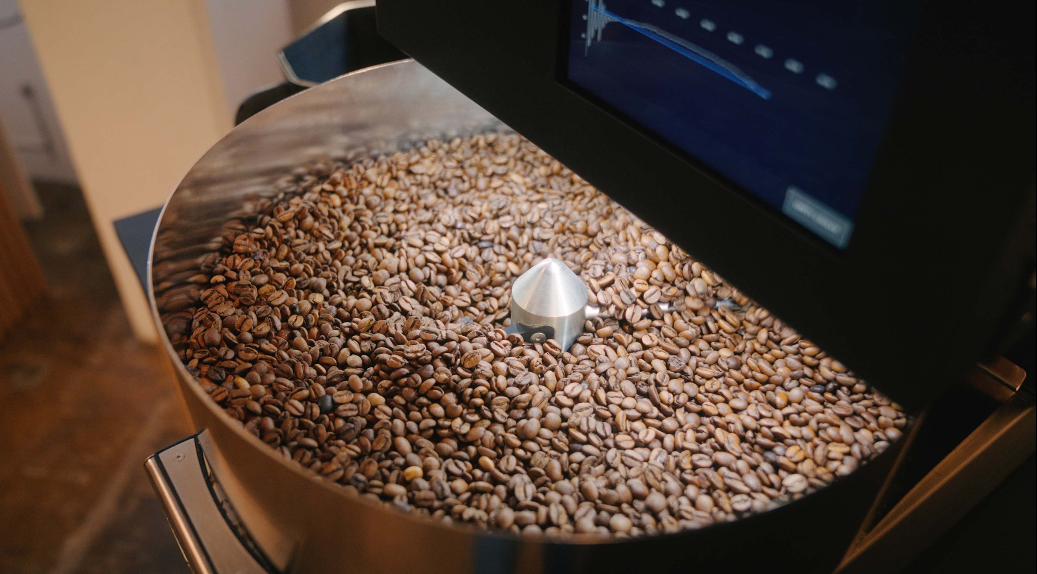 Roest coffee roaster filled with freshly roasted coffee beans on a wooden surface