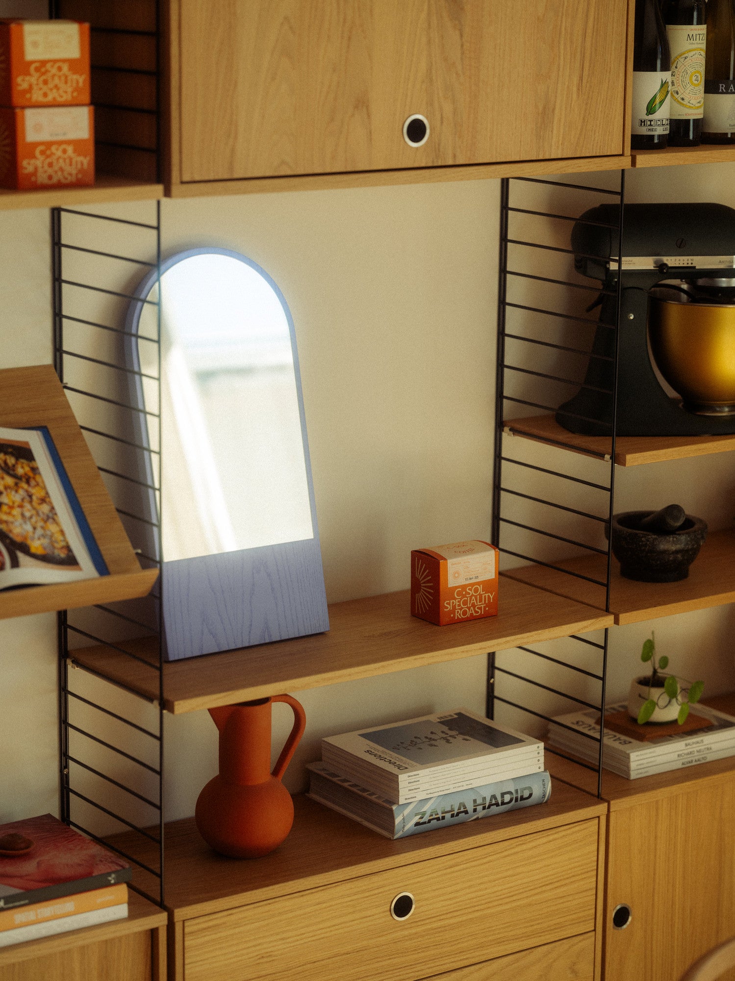 Wooden shelf with a mirror, books, and decorative items.