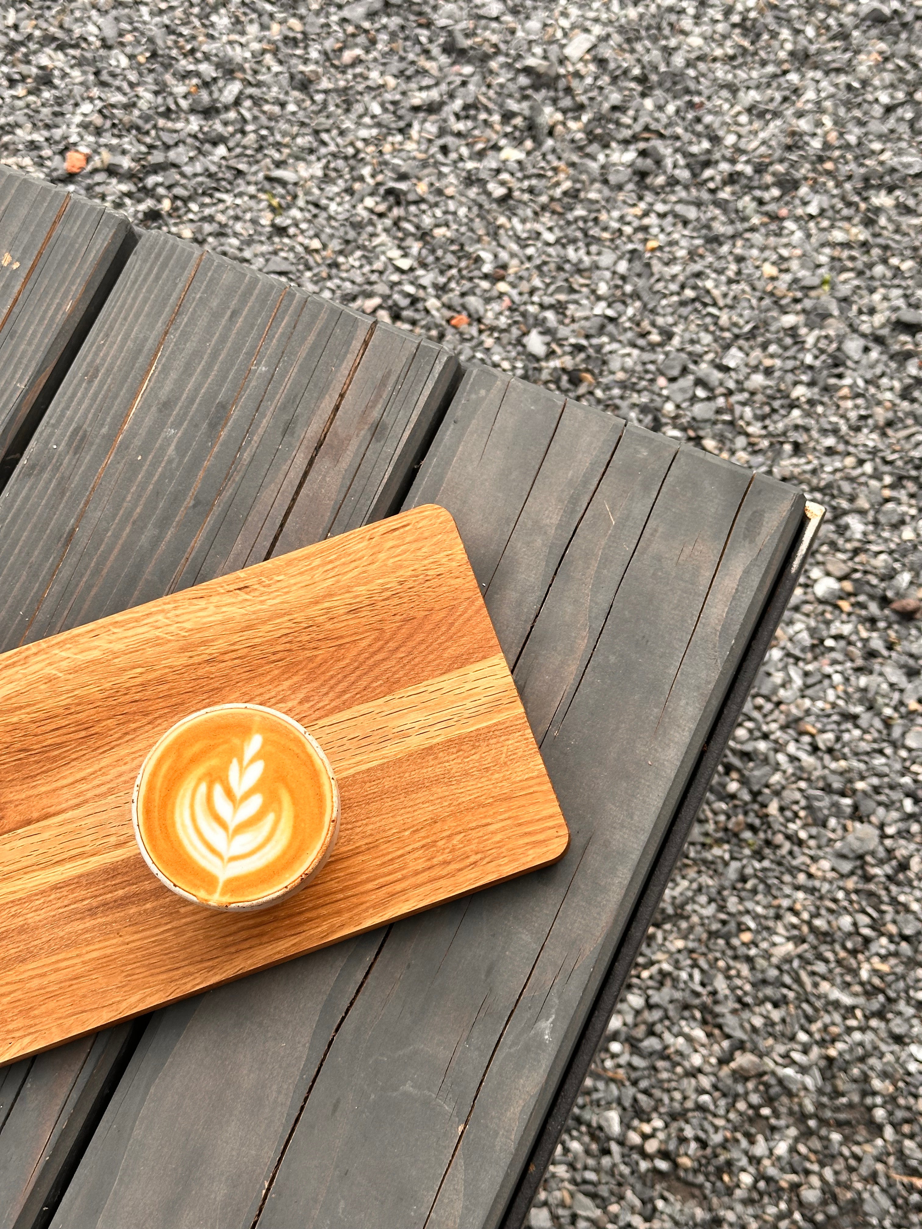 Wooden board with a cappuccino with latte art on a wooden surface